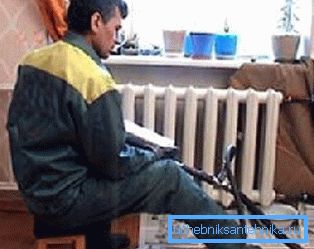 Na fotografiji, vodoinstalater pere radijatore u stanu Na fotografiji, vodoinstalater pere radijatore u stanu